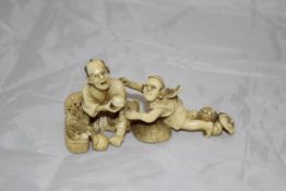 A Japanese carved ivory okimono as a man with basket of fruit and boy with mask at his feet