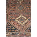 A Caucasian rug, the three central linked diamond shaped medallions in salmon, cream,