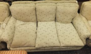 A three piece suite comprising a three seater sofa and two single armchairs in pale cream ground