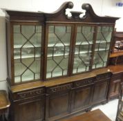 A Portugese mahogany breakfront display cabinet with swan neck moulded pediment over four astragal