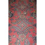 A Persian style runner in blues and greens on a burgundy ground,