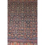 A Shenna rug, the dark blue centre field with all-over repeating motifs in terracotta,