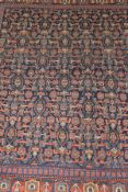 A Shenna rug, the dark blue centre field with all-over repeating motifs in terracotta,