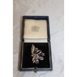 An 18 carat white gold ruby and diamond brooch set as a floral spray with leaf