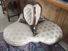 A Victorian three seat conversation sofa with a carved walnut frame,