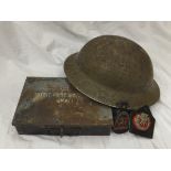 A box containing a collection of First World War memorabilia to include regimental badge,