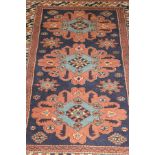 A Kazak rug with three central lozenge medallions on a blue ground,