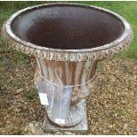 A large iron garden garden urn with egg and dart rim to the fluted shaped sides on a square base