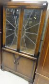 An early 20th Century oak display cabinet with leaded glazed doors above two enclosed doors below,