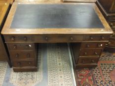 A mahogany nine drawer pedestal desk with black rexine inset top and turned wooden handles,