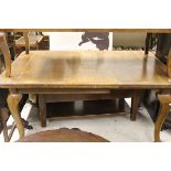 A circa 1900 oak rounded rectangular dining table on cabriole legs to pad feet and castors