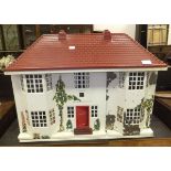 A mid 20th Century doll's house with sliding cream painted metal and decoupage decorated frontage,