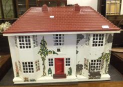 A mid 20th Century doll's house with sliding cream painted metal and decoupage decorated frontage,