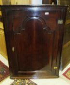 An oak four shelf wall hanging corner cabinet with panelled door