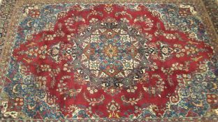 A Persian rug, the red ground with central motif in blue, red, peach, pink, cream,