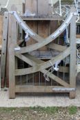 A pair of hardwood gates, the top rail arching down to the centre with various fittings, hinges,