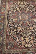 An Isfahan rug, the central floral medallion in ruby, teal and cream, on a dark blue,