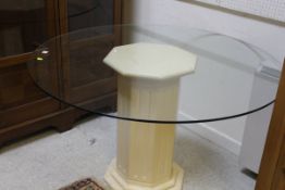 A modern circular glass topped table with central pedestal base