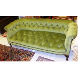 An Edwardian upholstered and button decorated green velvet sofa