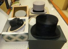 A collection of hats to include two grey felt top hats, a black silk top hat,