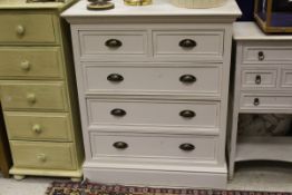 A white painted chest of two short and three long drawers with brass handles,