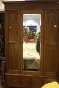 A Edwardian walnut single door wardrobe with mirrored door above single drawer,