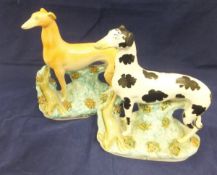 A collection of four large Staffordshire pottery greyhound figures with hare prey