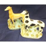 A collection of four large Staffordshire pottery greyhound figures with hare prey