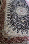 A Persian rug with central wheel pattern in white, sage green, reds, pinks,