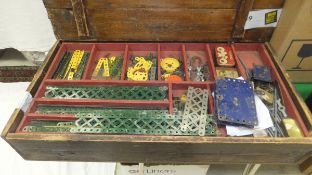 A wooden box containing an assortment of vintage Meccano