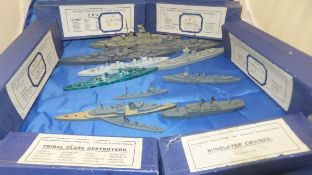 A box containing a collection of miniature painted wooden naval battle ships by Dinky,