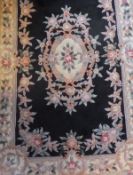 A Chinese superwash carpet in shades of pink, salmon, green, cream and blue on a black ground,
