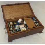 A wooden box containing a collection of costume jewellery, badges, buttons,