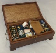 A wooden box containing a collection of costume jewellery, badges, buttons,