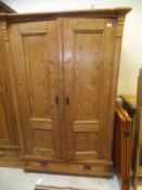 A vintage pitch pine two door wardrobe with single drawer, on bun feet,