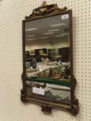 An early 20th Century gilt framed wall mirror with Art Nouveau style characters to the bottom