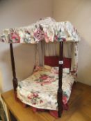 A mahogany four poster dog bed with upholstered canopy and covers
