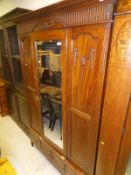 A Edwardian walnut single door wardrobe with mirrored door above single drawer,