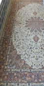 An Oriental rug, the central circular stylised floral decorated medallion in cinnamon, taupe,