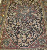 An Isfahan rug, the central floral medallion in ruby, teal and cream, on a dark blue,