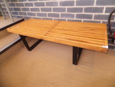 A slatted wooden bench with black stained supports in the manner of George Nelson for Hermann