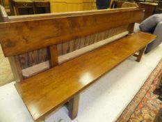 An oak bench of plank form on square supports united by a centre stretcher