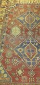 A Caucasian rug with repeating lozenge shaped medallions on a red ground,