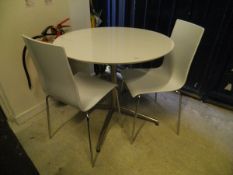 A circular white topped breakfast table and two chairs with brushed steel bases