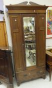 An Edwardian walnut single mirror door wardrobe with drawer