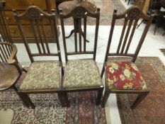 A set of five early to mid 20th Century oak framed slat back dining chairs with carved floral motif