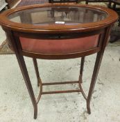 An oval glass topped bijouterie table on slender square sectioned legs,