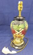 A Moorcroft Pottery table lamp decorated with lilies in red and orange on a cream ground,