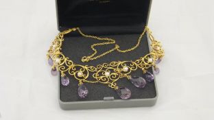 A yellow metal mounted filigree work necklace set with seed pearls and amethyst coloured glass