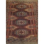 A Bokhara rug, the central panel set with four repeating elephant foot medallions on a rust ground,